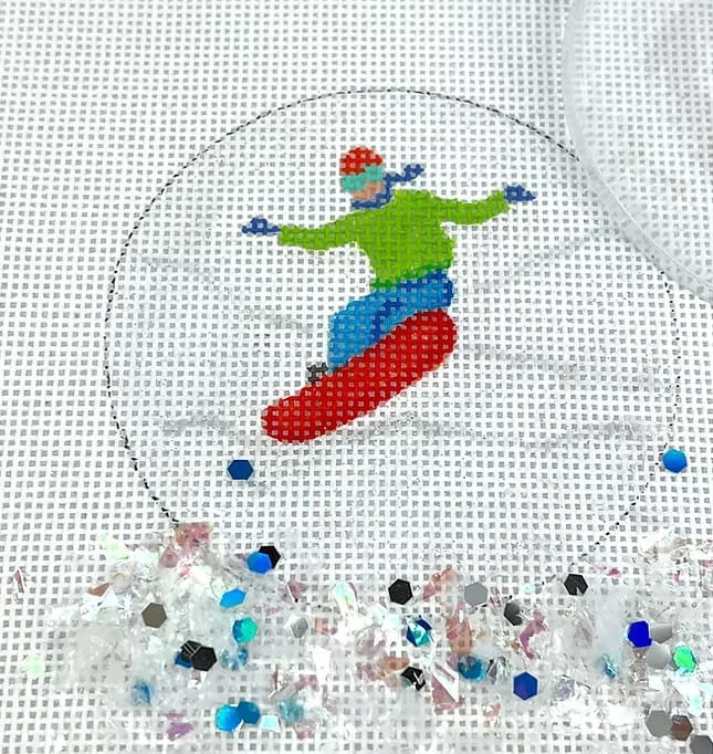 Kate Dickerson Needlepoint – 3″ Round w/Clear Dome & Confetti – Snowboarder